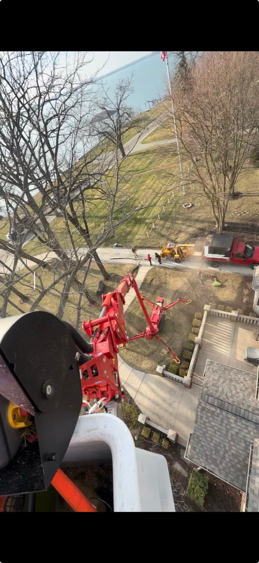 View from inside the CMC 90HD Arbor Pro basket — boom deployed over a residential lakefront yard